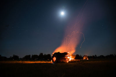 Fire on field against sky at night