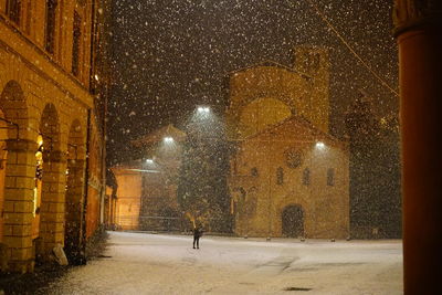 Rear view of man walking on illuminated street in city at night