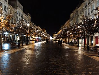 Illuminated street amidst buildings in city at night