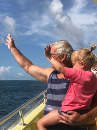 Senior man holding granddaughter in boat on sea