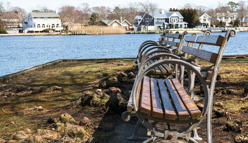 Empty chairs by river against buildings