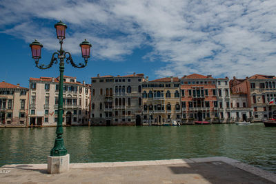 Buildings by canal against sky in city