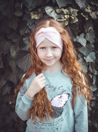 Portrait of girl with brown hair standing against plants