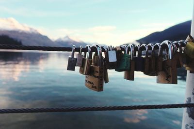 Close-up of padlocks on railing against sky