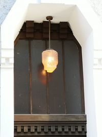 Low angle view of illuminated lamp hanging on building