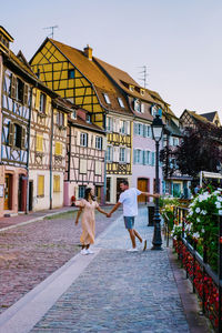 Rear view of people walking on street amidst buildings