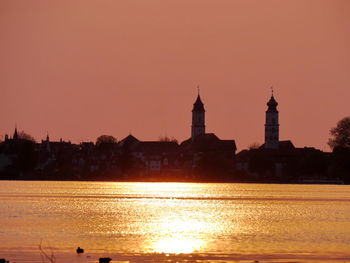 Buildings in front of lake constance against clear sky during sunset