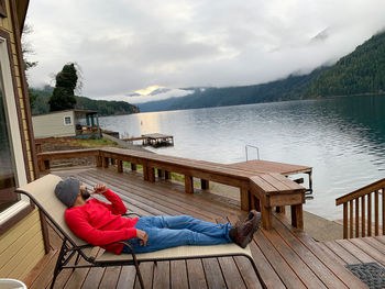 People relaxing by lake against sky