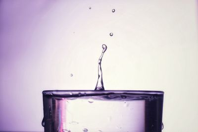 Close-up of water splashing on glass against white background