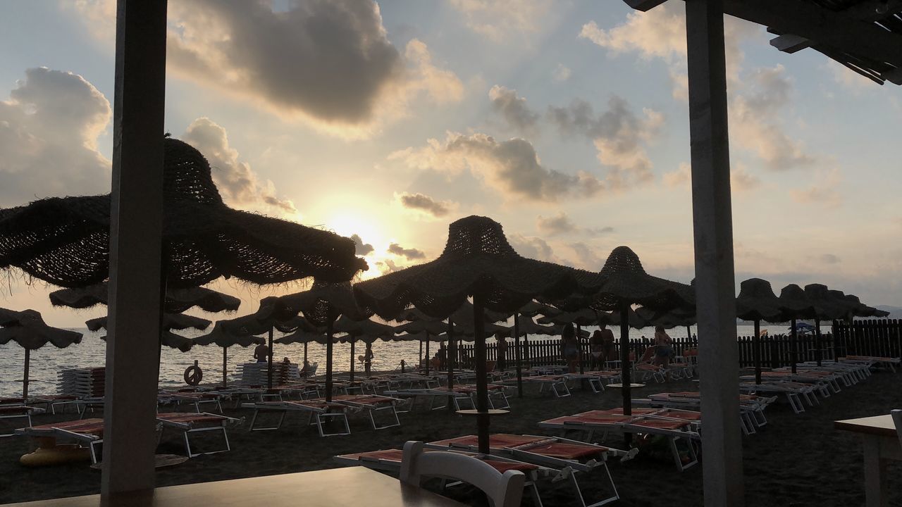 CHAIRS ON BEACH AGAINST SKY DURING SUNSET