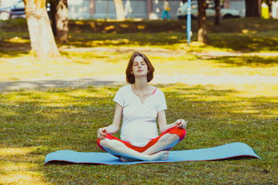 Full length of young woman sitting on grass