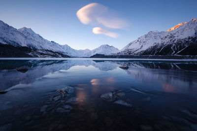 Scenic view of lake and snowcapped mountains against sky