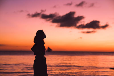 Silhouette woman standing at beach during sunset