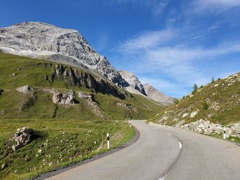 Road by mountains against sky