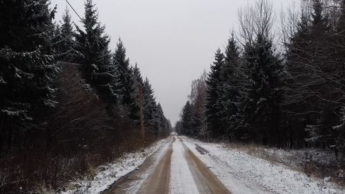 Road amidst trees against clear sky during winter