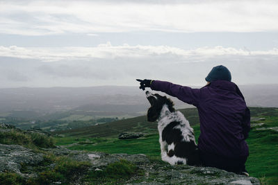 Woman with dog standing on mountain against sky