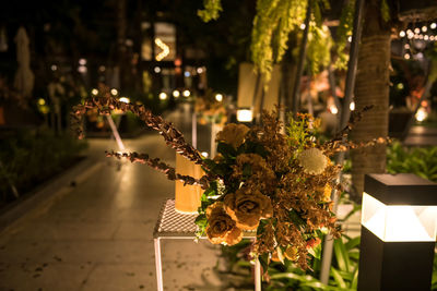 Artificial golden flowers and candle decoration in night outdoor wedding ceremony in resort garden.