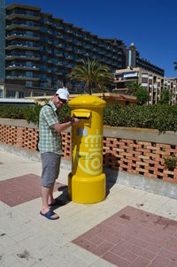 Full length of man standing on yellow sidewalk in city