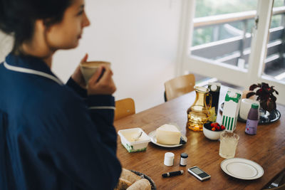Woman suffering from diabetes having coffee by breakfast on table at home