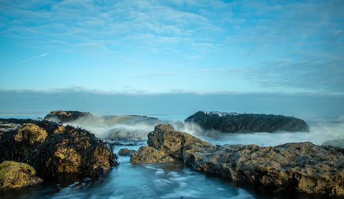 Scenic view of rocks in sea against sky