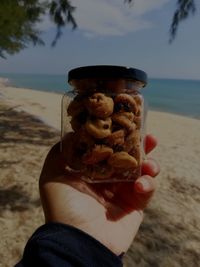 Midsection of person holding ice cream on beach