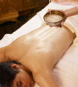 High angle view of shirtless man lying down on massage table