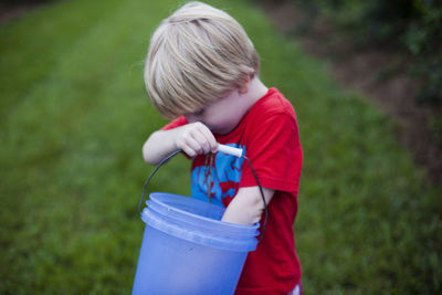 Boy holding blue umbrella while standing on grass