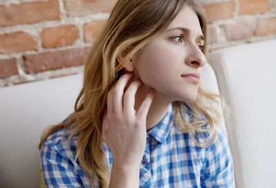 Close-up of young woman looking away while sitting against wall