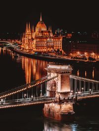 Illuminated bridge over river at night