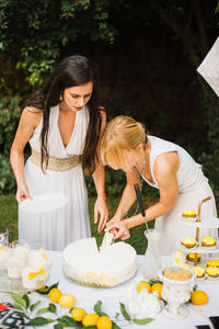 Two girls in white dresses cuting the cake