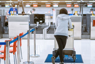 Back view of airline passenger wear face mask to prevent  covid-19 wait to check in airport