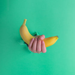 Close-up of hand holding apple against blue background