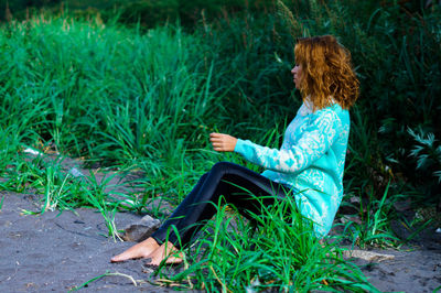 Full length of woman sitting on dirt against plants