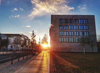 Street amidst buildings against sky during sunset