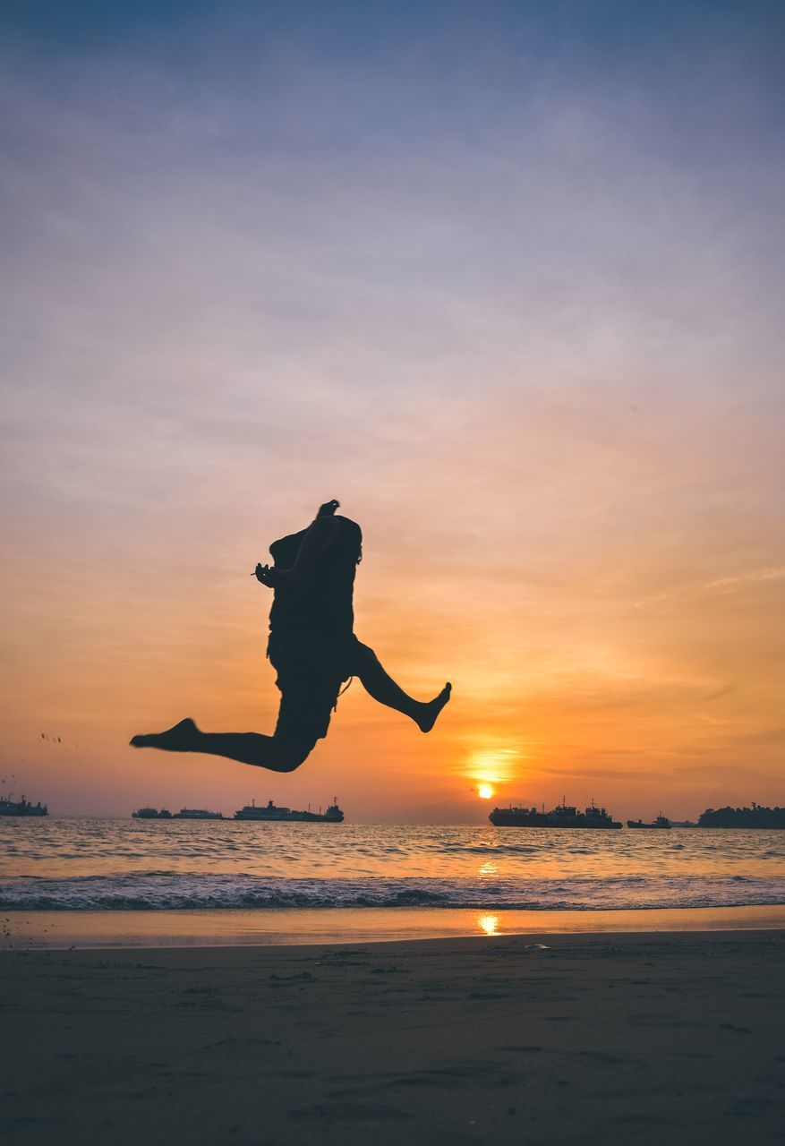 SILHOUETTE MAN JUMPING AT BEACH DURING SUNSET