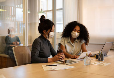 Businesswomen wearing mask having discussion at office