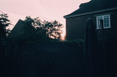 Low angle view of silhouette tree by building against sky