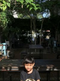 Boy with eyes closed sitting outdoors during sunny day