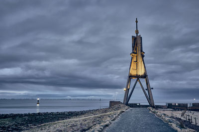 Tower by sea against sky