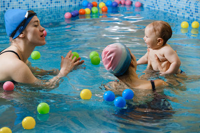 Early age swimming in pool. baby boy trained to swim in water coach woman in indoor swimming pool  