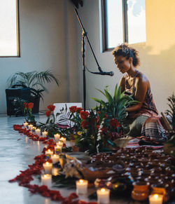 Woman sitting by potted plant on table at home