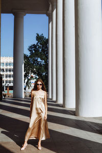 Full length of fashionable young woman standing by building in city