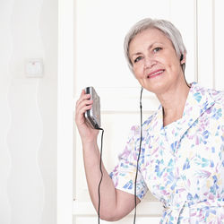 Gray-haired senior woman in avintage dress with portable stereo radio cassette player  retro concept