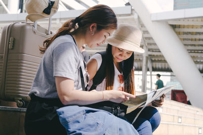 Tourists reading map while sitting on steps in city