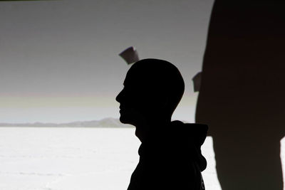 Side view of silhouette bald man standing against sky