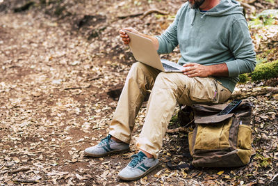 Midsection of man using mobile phone while sitting on land