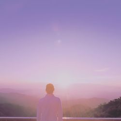 Rear view of man standing on mountain against sky