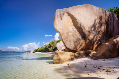 Rock formation on beach against blue sky