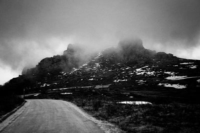 Road leading towards mountain against sky