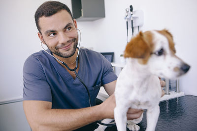 Close-up of smiling veterinarian examining puppy in hospital